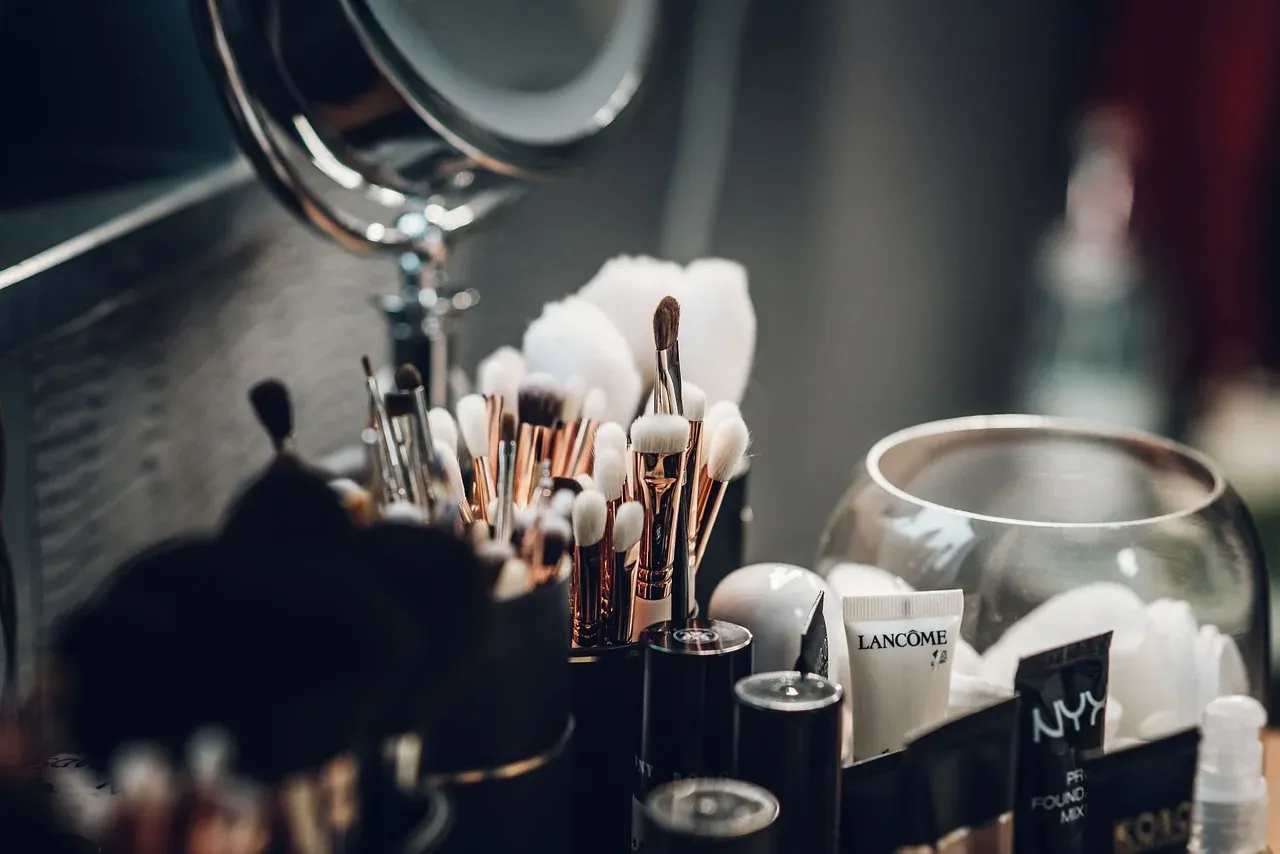 Brushes, lipsticks and cosmetics on a make-up table.