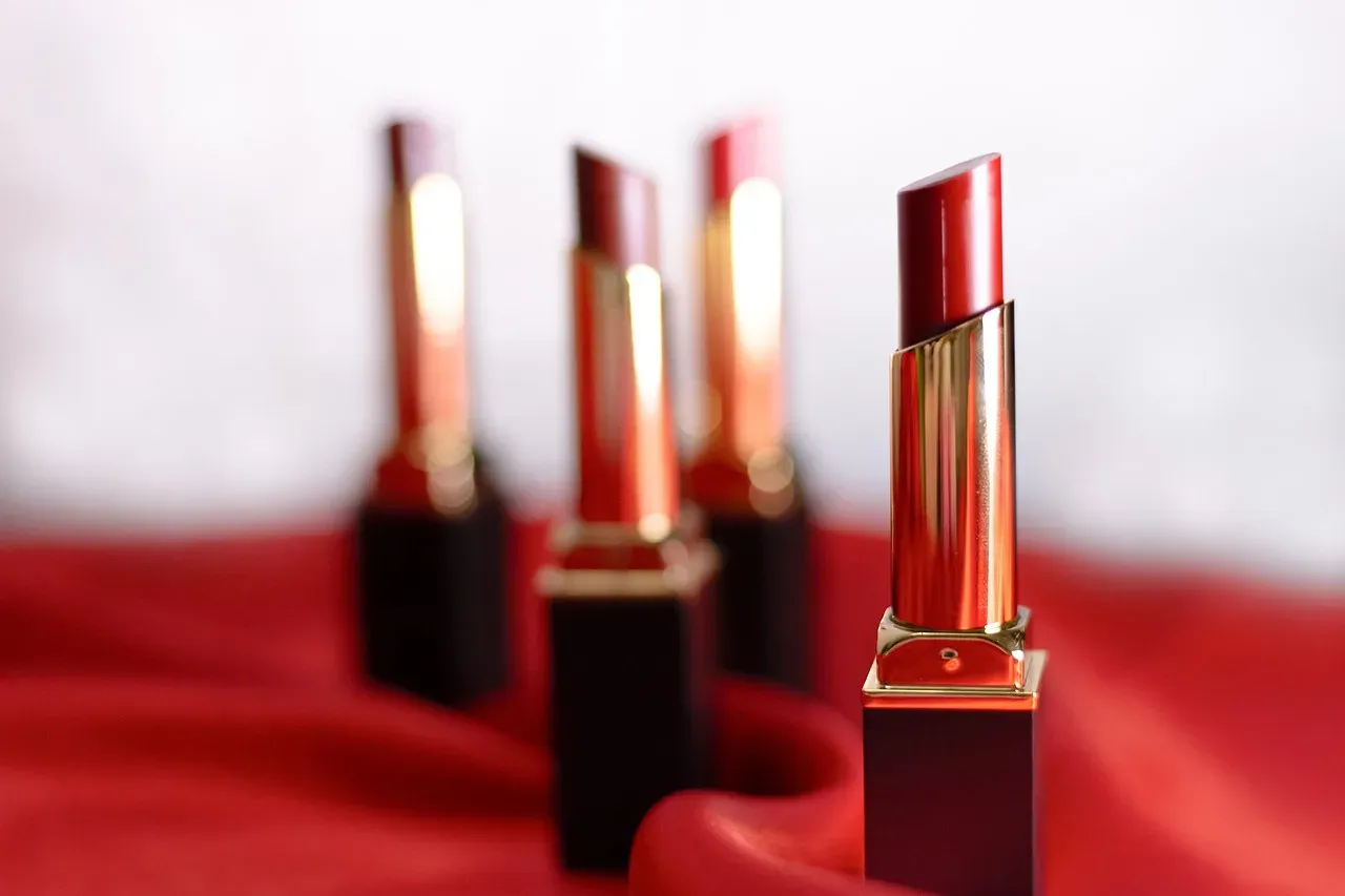Red lipsticks in gold cases standing on red satin.